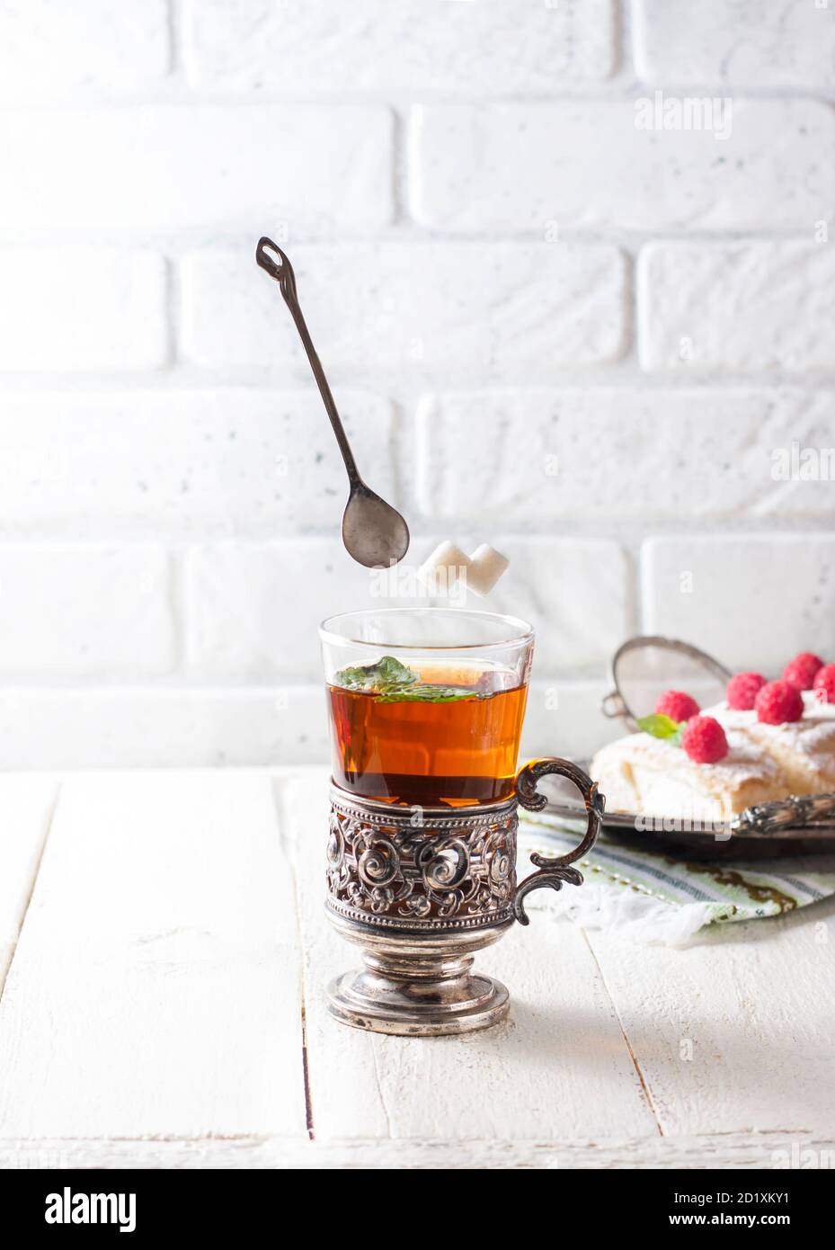 Tea on a light background and ingredients flying in the air, sugar,, spoon. Bursts, splashes. Vintage. Stock Photo