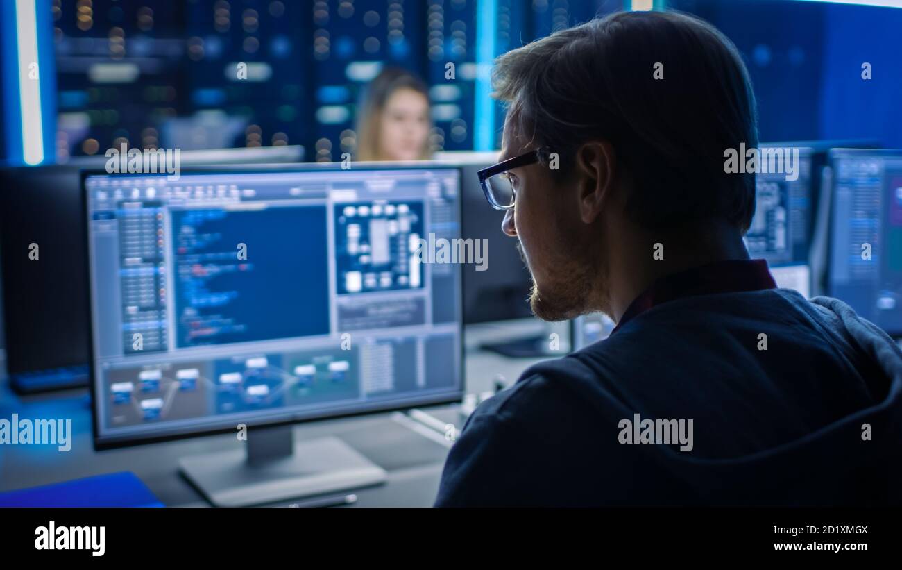 Smart Male IT Programer Working on Desktop Computer in Data Center Technical System Control Room. Team of Young Professionals Programming in Coding Stock Photo