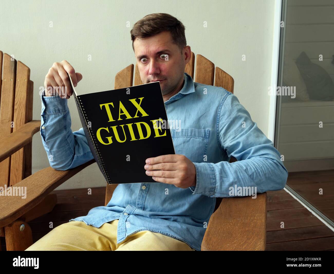 Tax guide concept. A guy sitting in a chair reads a book. Stock Photo