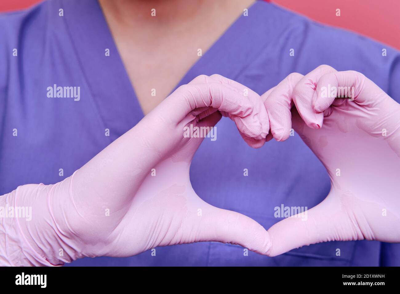 The medic shows the heart sign with his fingers, close-up. Doctor's hands in medical gloves with the sign of love for patients, concept. Stay home. Stock Photo