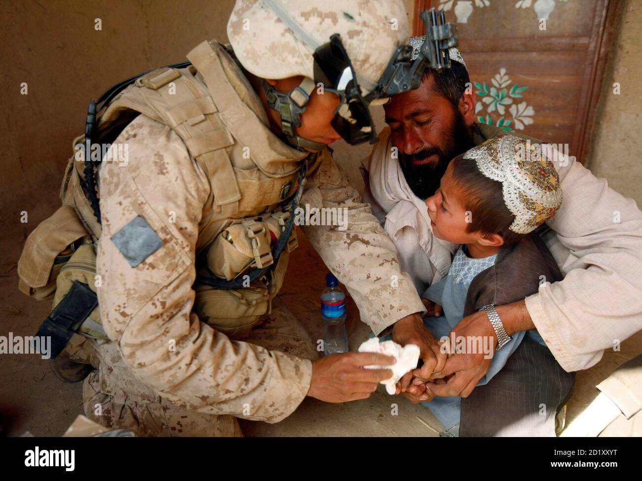 A U.S. Marine from Lima company 3rd Battalion 6th Marine Regiment administers first aid to a child during a patrol in Karez-e-Sayyidi, in Helmand province, April 5, 2010. REUTERS/Asmaa Waguih  (AFGHANISTAN - Tags: CIVIL UNREST MILITARY CONFLICT) Stock Photo