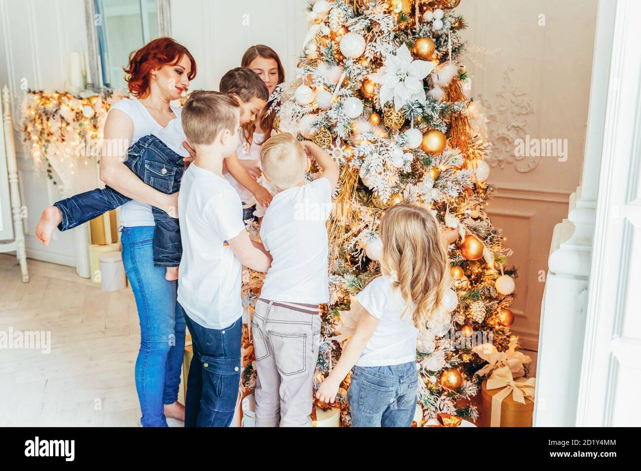 Happy family mother and five children decorating Christmas tree on