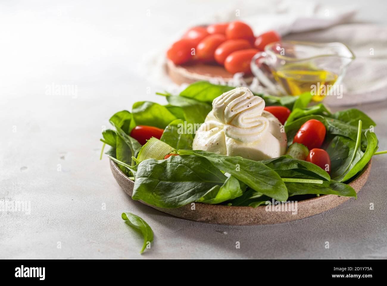 faktureres vogn hoppe Italian cheese burrata with a salad of fresh spinach, cucumbers and cherry  tomatoes with olive oil in a ceramic plate on a light background Stock  Photo - Alamy