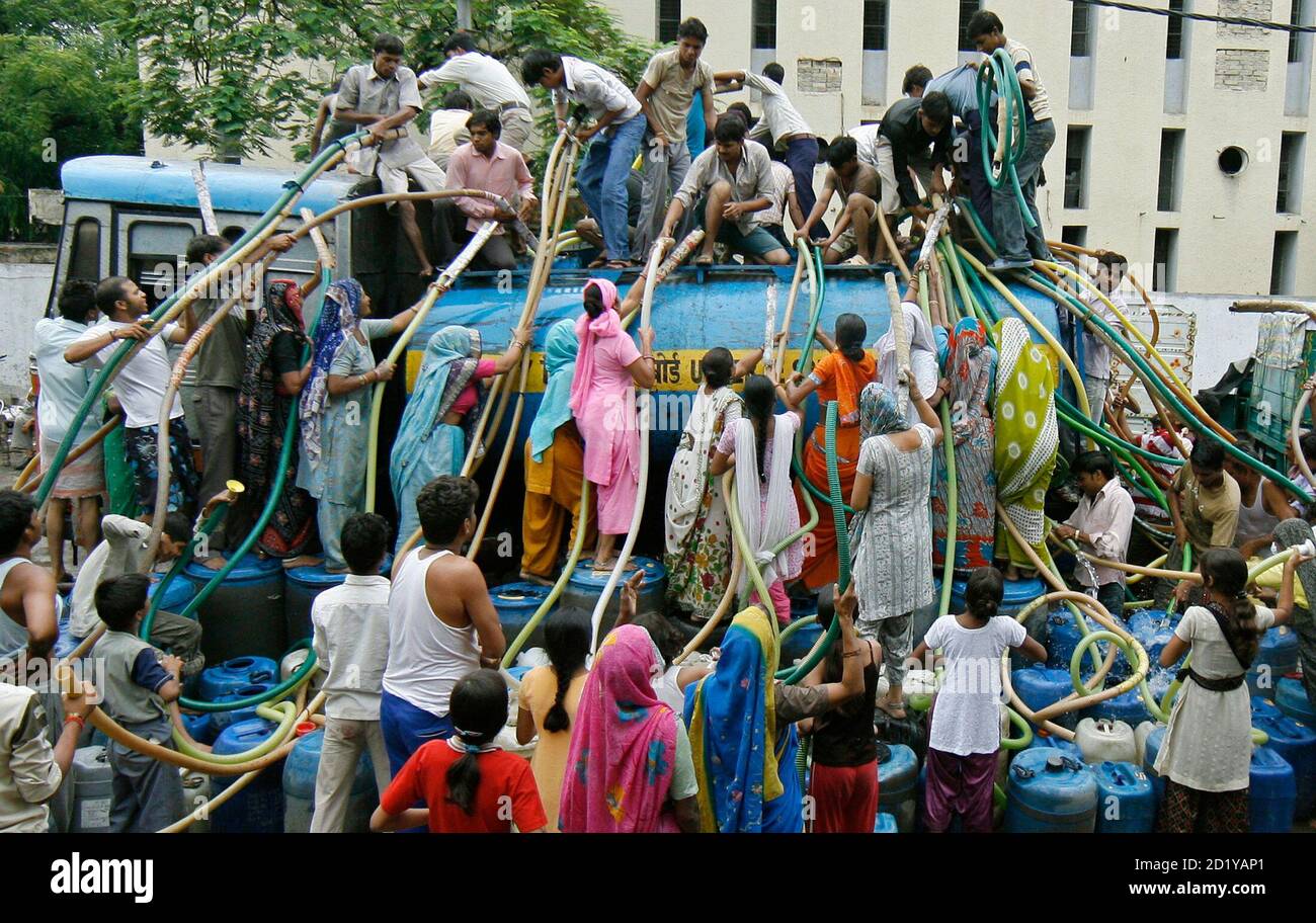 Residents of Sanjay Colony, a residential neighbourhood, crowd around a water tanker provided by the state-run Delhi Jal (water) Board to fill their containers in New Delhi June 30, 2009. Delhi Chief Minister Sheila Dikshit has given directives to tackle the burgeoning water crisis caused by uneven distribution of water in the city according to local media. The board is responsible for supplying water in the capital. REUTERS/Adnan Abidi (INDIA ENVIRONMENT SOCIETY) Stock Photo