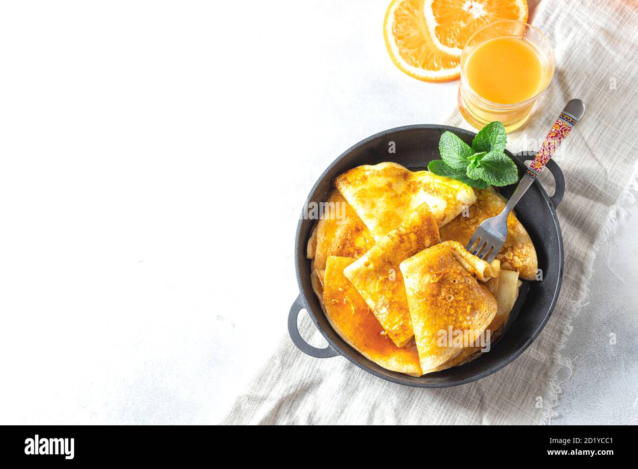 Crepes with Orange Sauce in a cast iron pan. Traditional French crepe Suzette with orange sauce. Stock Photo