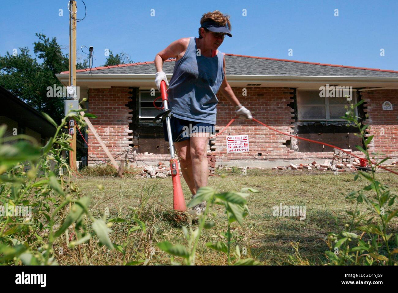 Kathy Singleton cuts weeds in front of her vacant house in the Lakeview area of New Orleans, Louisiana, August 25, 2007. New Orleans continues to recover from the damage incurred when Hurricane Katrina struck the city almost two years ago on August 29, 2005. REUTERS/Lee Celano (UNITED STATES) Stock Photo