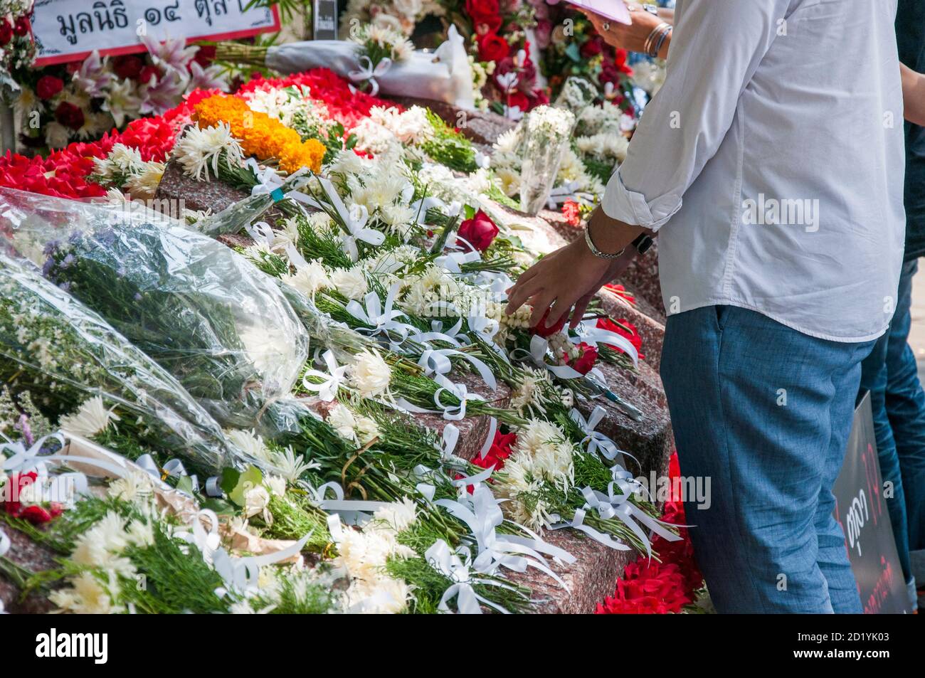 A person lays flowers in the memorial for the victims of the Thammasat University Massacre.The 6 October 1976 Thammasat University massacre was a violent crackdown by Thai police joined with right-wing paramilitaries against leftist protesters and students who had occupied Bangkok's Thammasat University. Stock Photo