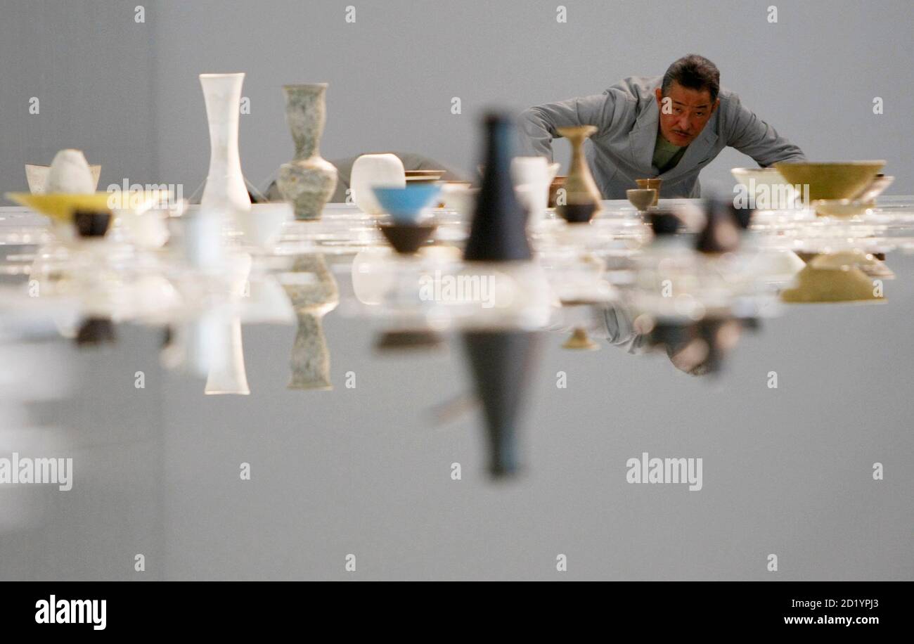 Japanese designer Issey Miyake poses with artworks by Austrian potter Lucie Rie at the exhibition 'U-Tsu-Wa' in Tokyo February 10, 2009. Miyake, the designer whose name became a byword for Japan's economic and fashion prowess in the 1980s, believes good design is a necessity, even in tough times. Picture taken February 10, 2009.     REUTERS/Kim Kyung-Hoon (JAPAN) Stock Photo
