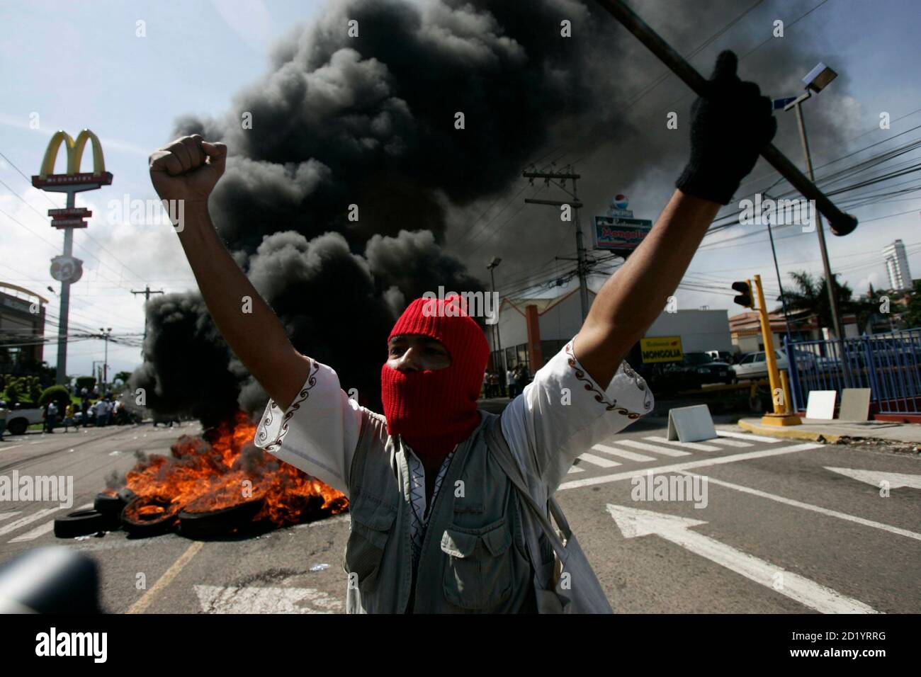 A supporter of Honduras' President Manuel Zelaya demonstrates in front of burning tires outside the presidential residency in Tegucigalpa June 28, 2009. Witnesses said Zelaya was detained at home by troops in a constitutional crisis over his attempt to win re-election. CNN's Spanish-language channel later quoted Costa Rican officials as saying he was in Costa Rica and seeking political asylum. REUTERS/Edgard Garrido (HONDURAS CONFLICT POLITICS IMAGES OF THE DAY) Stock Photo