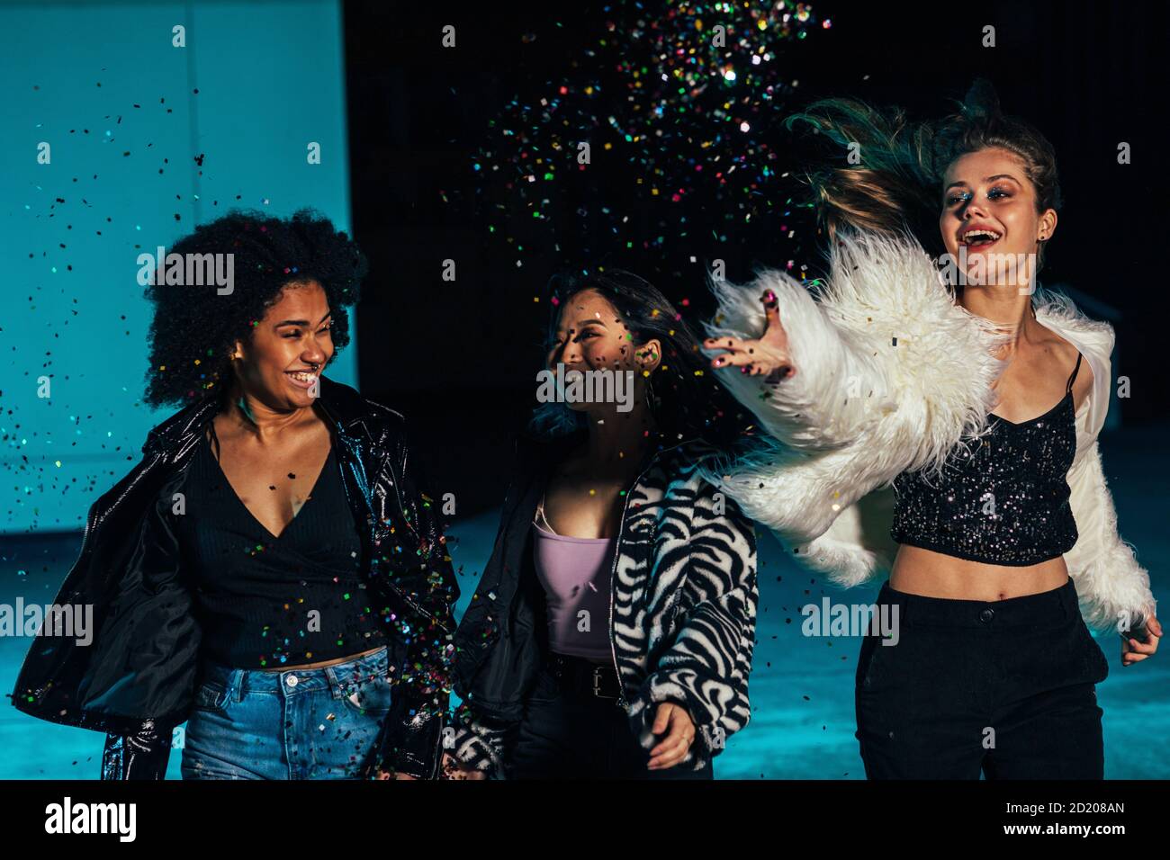 Three happy women running on roof and throwing confetti at night Stock Photo Alamy
