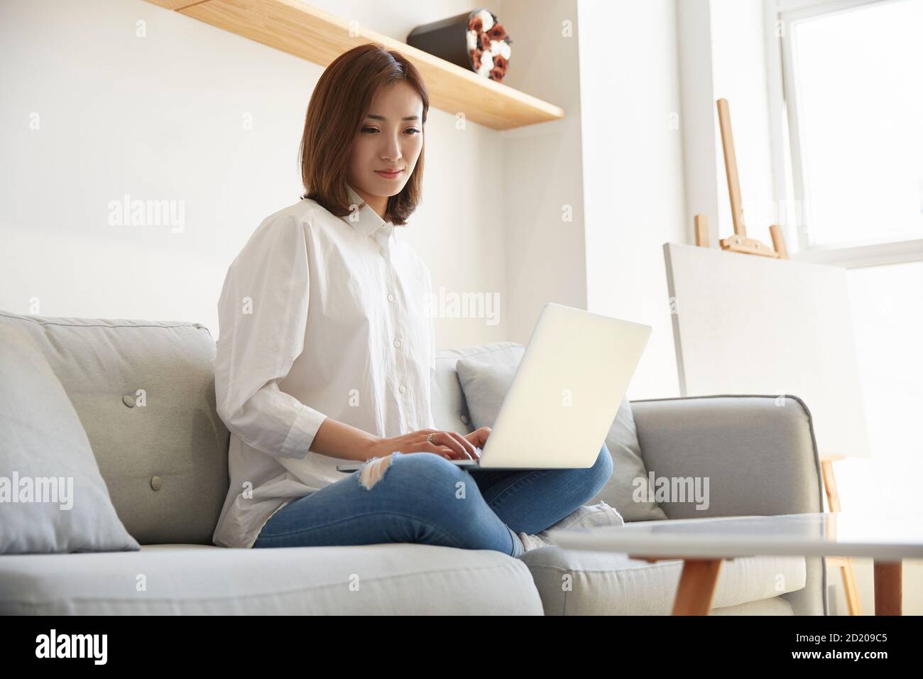 young asian business woman working at home sitting on couch using laptop computer Stock Photo