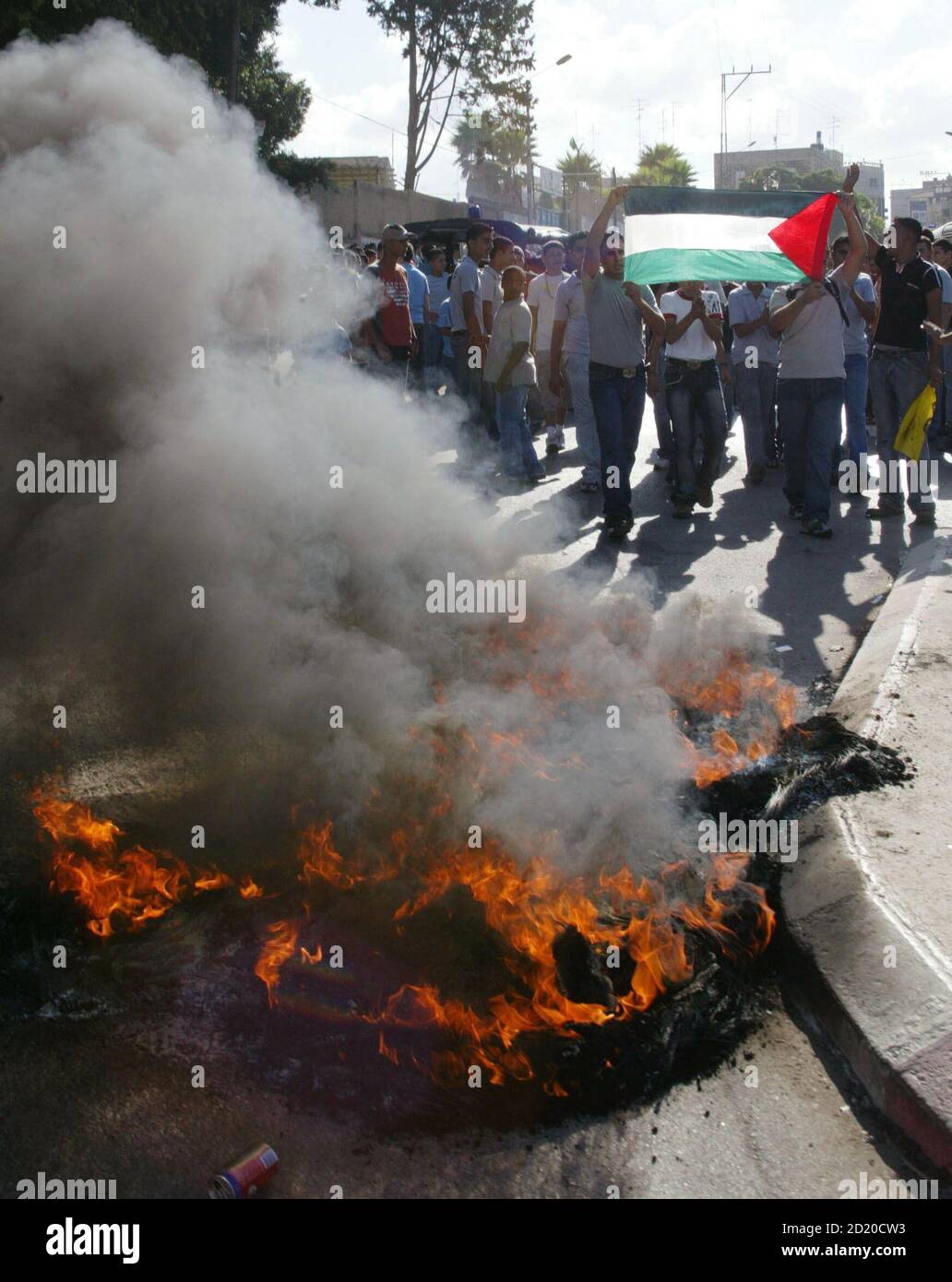 Palestinian students walk past burning tyres during a protest after government workers, including teachers, started an open-ended strike in the town of Tulkarm September 2, 2006. Tens of thousands of Palestinian government employees went on strike in the West Bank and Gaza on Saturday in protest against unpaid salaries and the perceived failings of the Hamas-led government. REUTERS/Mustafa Abu Dayeh  (WEST BANK) Stock Photo