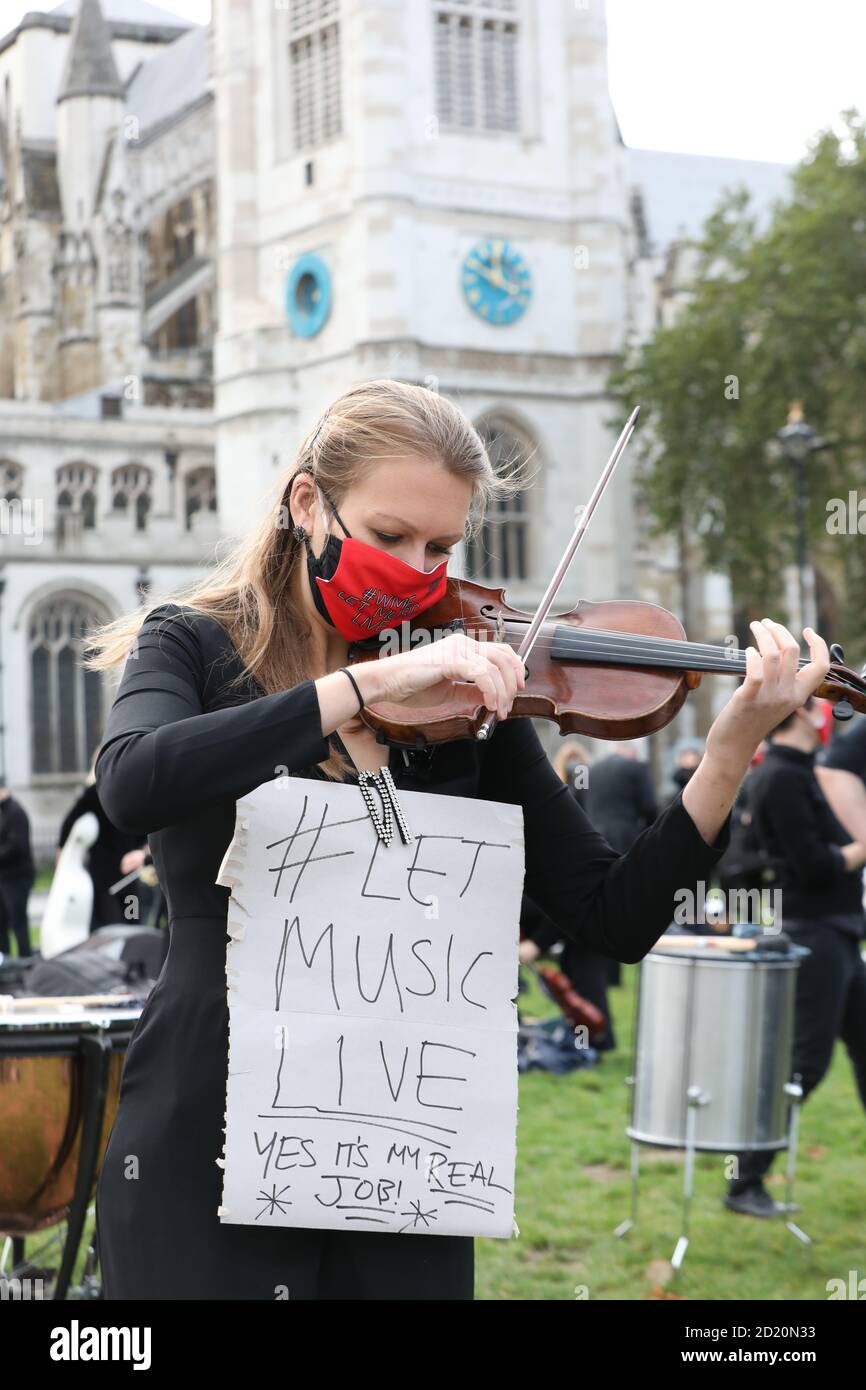 Freelance professional musicians, conducted by director David Hill, perform a section of 'Mars' from Holst's 'The Planets' in Parliament Square, Westminster, London. The Let Music Live campaign is raising awareness of the need for targeted support for freelance musicians during the coronavirus pandemic and calling on the Government to recognise that freelance musicians are an economic asset. Stock Photo