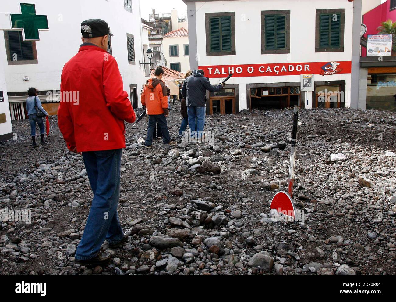 People walk over the debris on a downtown Funchal street after heavy  flooding in Madeira island February 21, 2010. Portuguese rescue workers  using bulldozers searched on Sunday for more bodies under debris