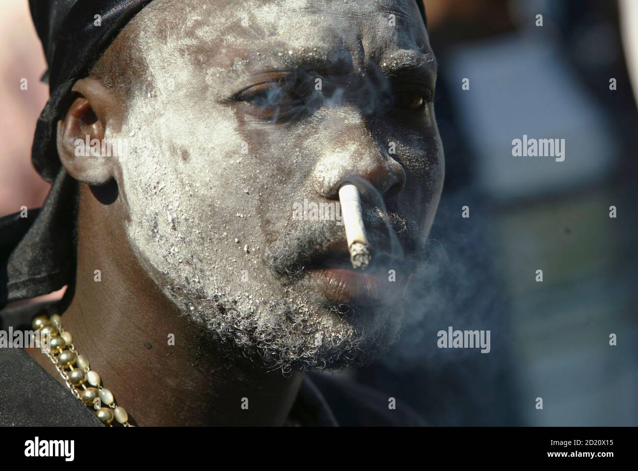 A voodoo believer dressed as 'Gede' the spirit of death smokes a cigarette  through his nose at a cemetery in Port-au-Prince November 2, 2006. Haitians  celebrating All Hallows visit cemeteries to pay