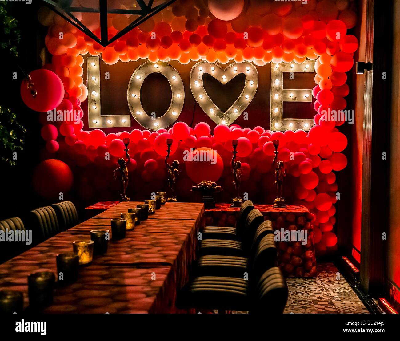 Romantic themed interior decor at restaurant for valentine's day with red  balloons and the word love in lights Stock Photo - Alamy