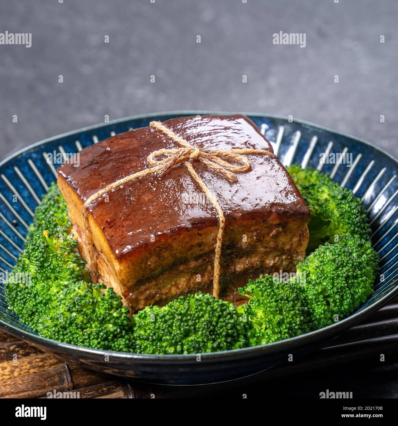 Dong Po Rou (Dongpo pork meat) in a beautiful plate with green vegetable, traditional festive food for Chinese new year cuisine meal, close up. Stock Photo