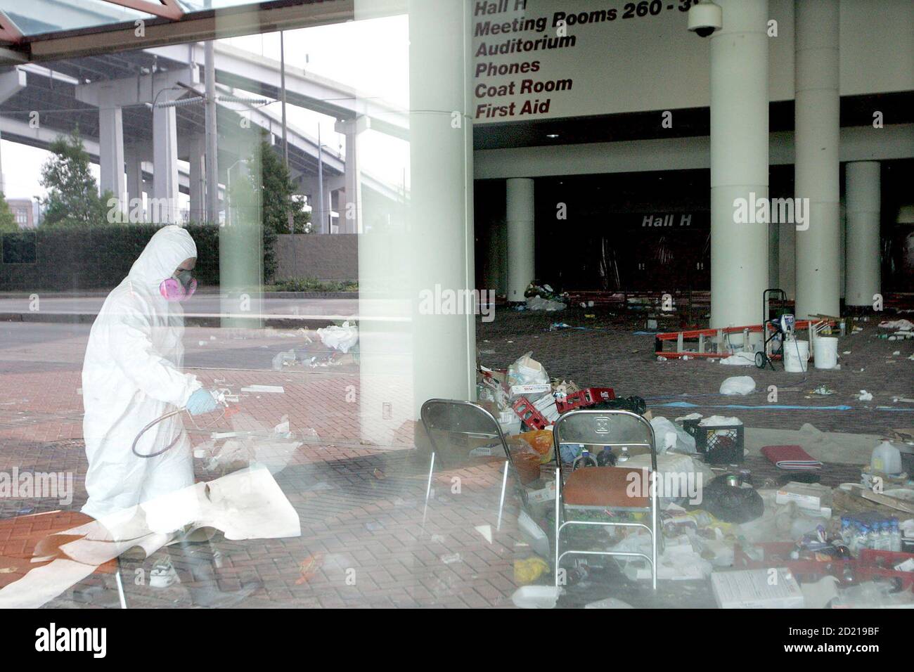 A worker wearing a protective suit sprays down the inside of the Convention Center where Hurricane Katrina evacuees were originally housed, in New Orleans, Louisiana, September 18, 2005. Federal and local authorities clashed on Sunday over whether New Orleans was ready for residents to return, putting in doubt efforts to quickly resettle the devastated city. REUTERS/Jessica Rinaldi  JR/PN Stock Photo