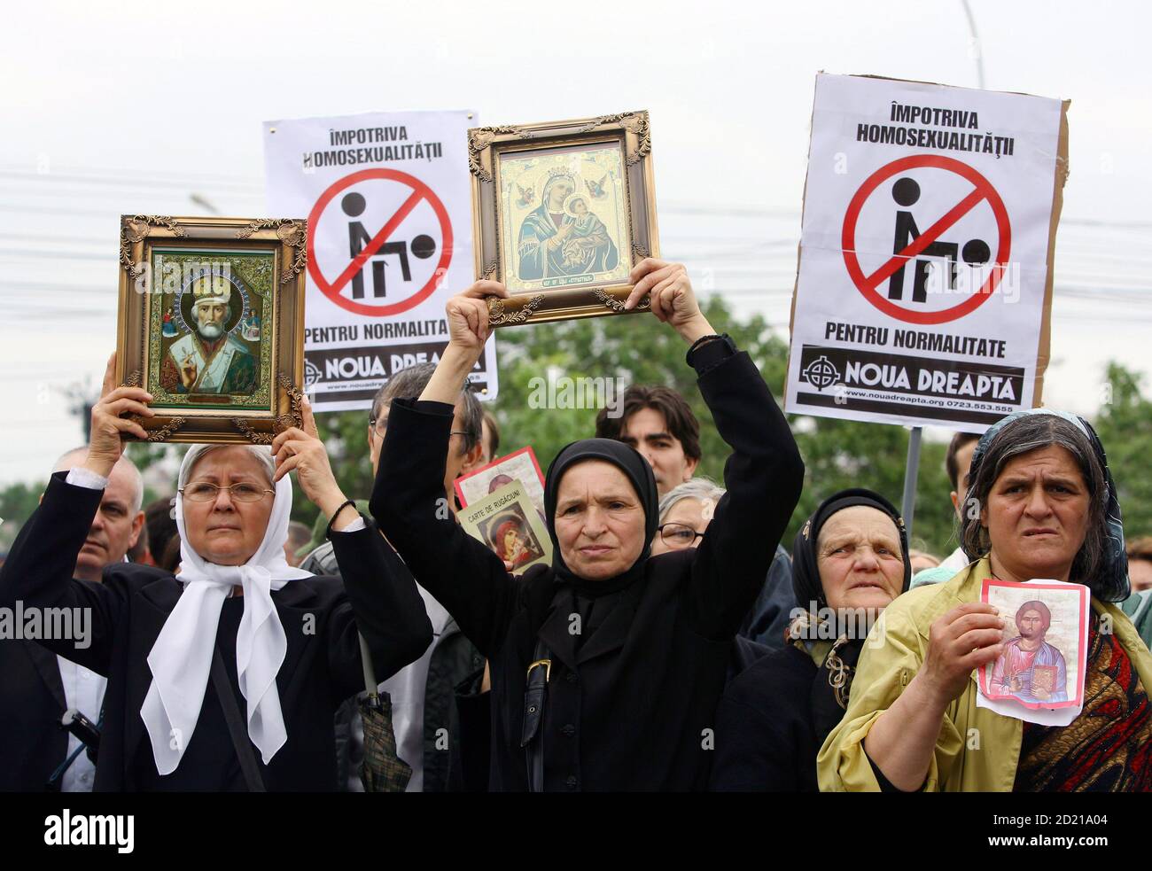Romanians hold Orthodox icons and anti-homosexuals signs during a protest against a scheduled gay parade through the capital, in Bucharest June 3, 2006. The banners read 'Against homosexuality - for normality. Stock Photo