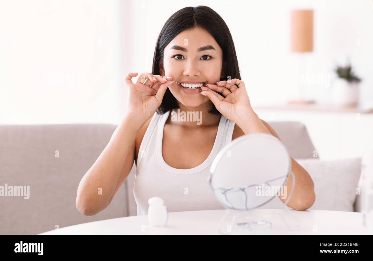 Young asian lady using dental floss looking in mirror Stock Photo Alamy