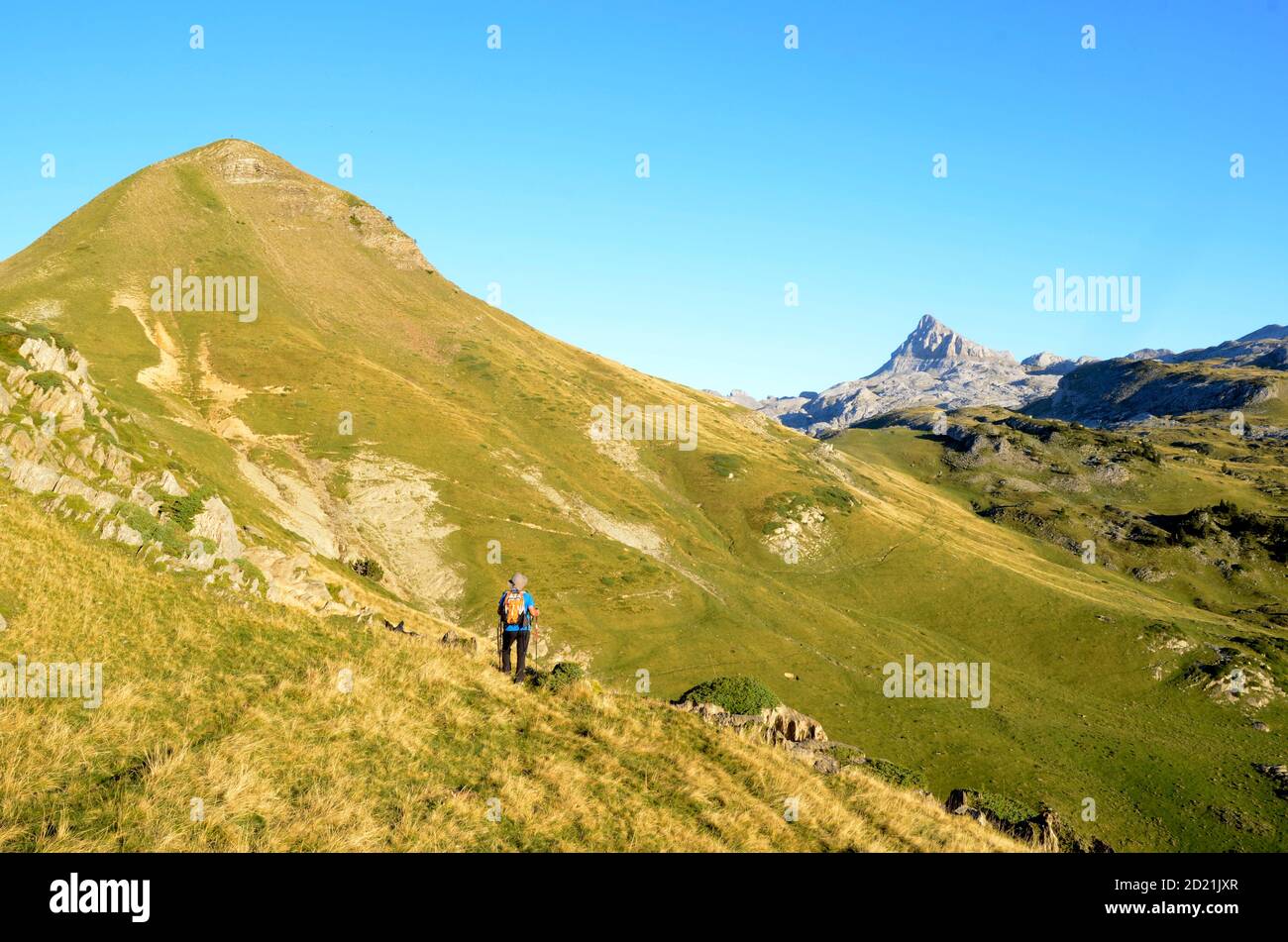 A mountaineer walks towards the Arlas (left) and Anie (background) mountains in the Pyrenees of France Stock Photo