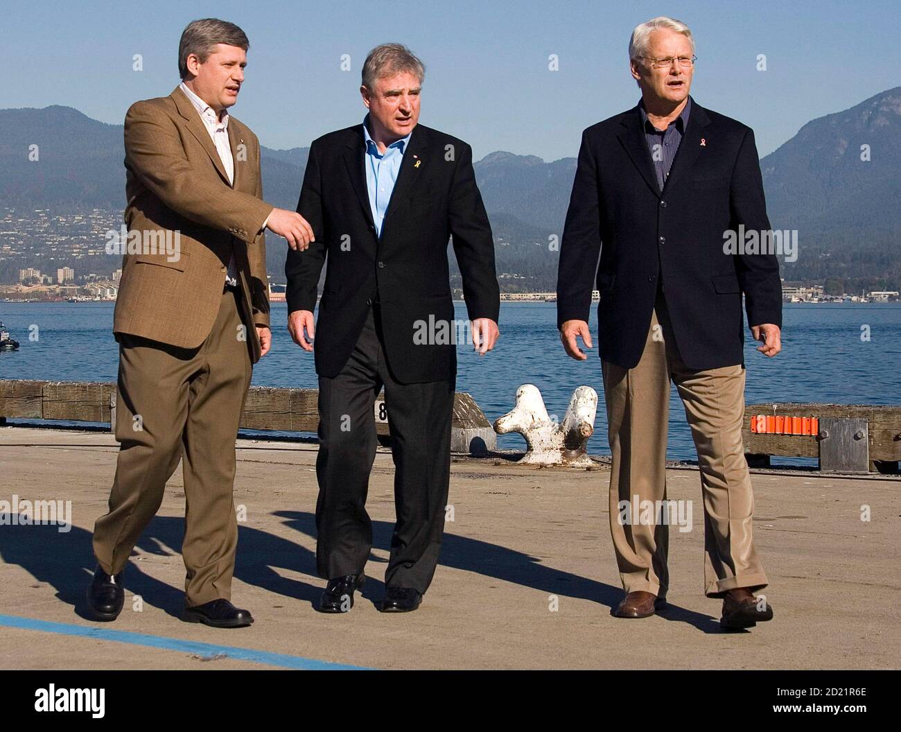 Canadian Prime Minister Stephen Harper (L), British Columbia Premier Gordon Campbell (R) and International Trade Minister David Emerson walk along the Balantyne Pier in Vancouver, British Columbia, October 11, 2006. Canada will pump almost C$600 million ($531 million) into upgrading ports, roads and railways on its West Coast in an attempt to clinch a bigger share of the growing Pacific shipping market.        REUTERS/Jeff Vinnick (CANADA) Stock Photo