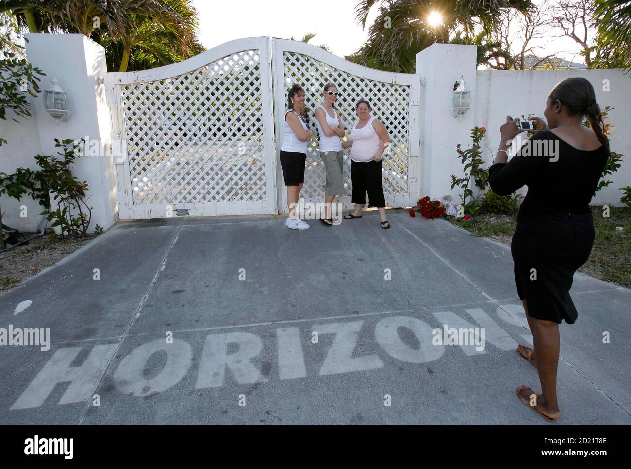 Deborah Palmer of Nassau (R) takes a photo of vacationers (L-R, rear)  Debbie Phillips, Justina Tisdell and Sandra Coss of Orlando as they pose  outside the gates to "Horizons" in Nassau, Bahamas,