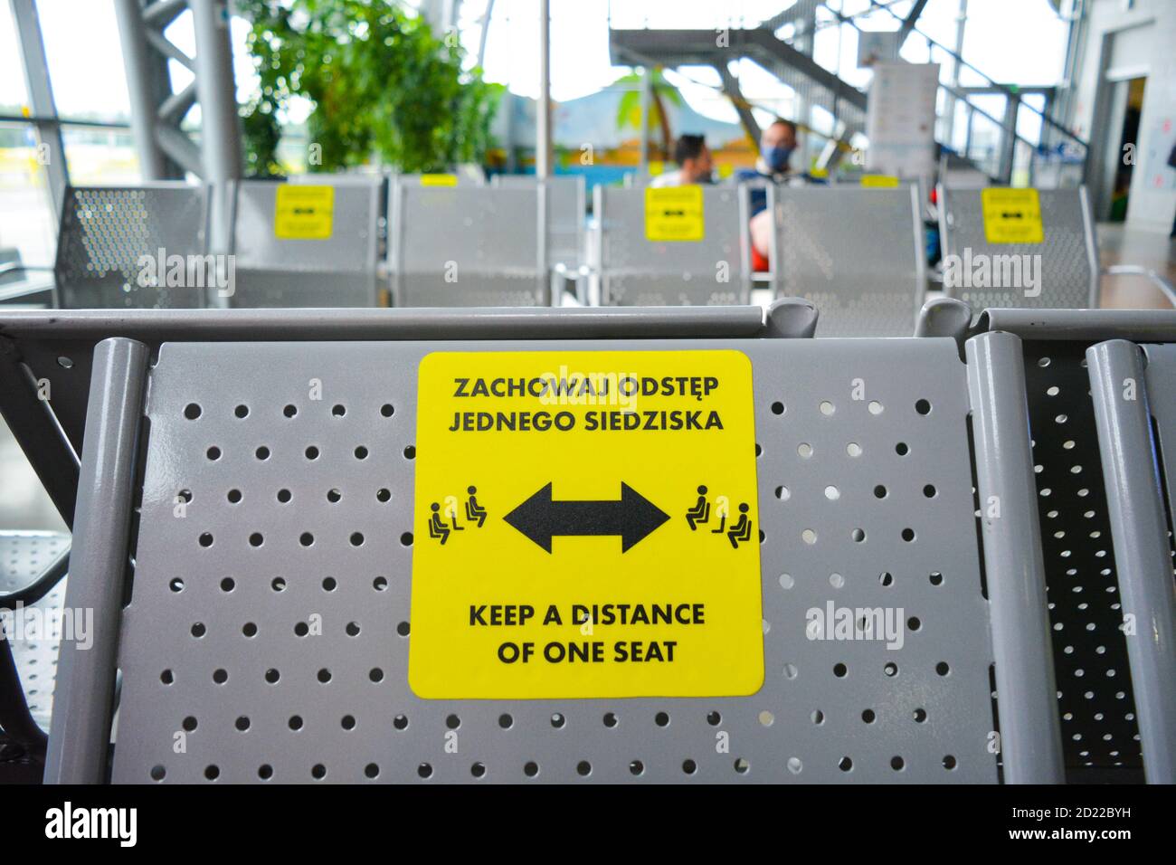 Social distancing measures in Poland (Polska) to prevent second wave of coronavirus. Sign in polish and english language on a chair in Modlin Airport Stock Photo