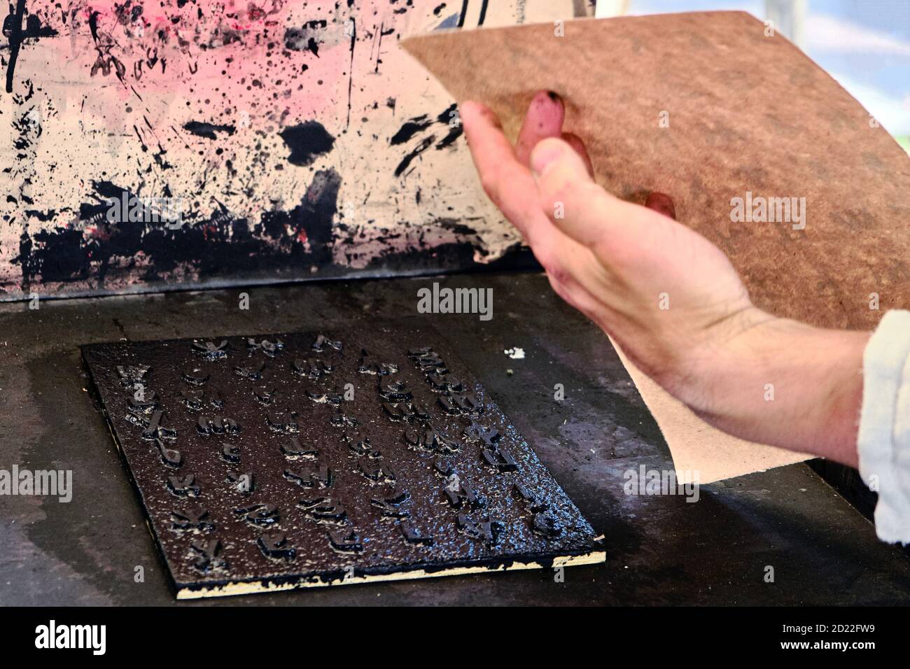 A man takes a printed sheet of paper. Printing books old retro method