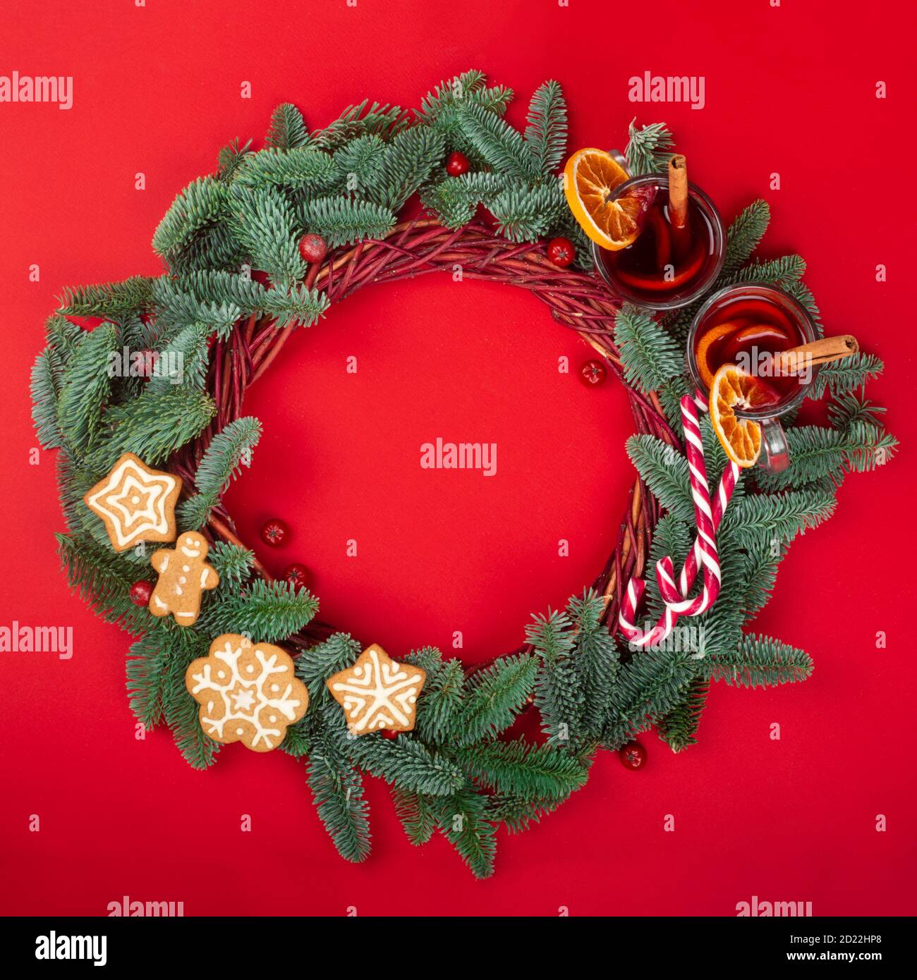 Christmas decorative wreath with noble fir tree twigs pine cones mulled wine and gingerbread cookies on red paper background with copy space for text Stock Photo