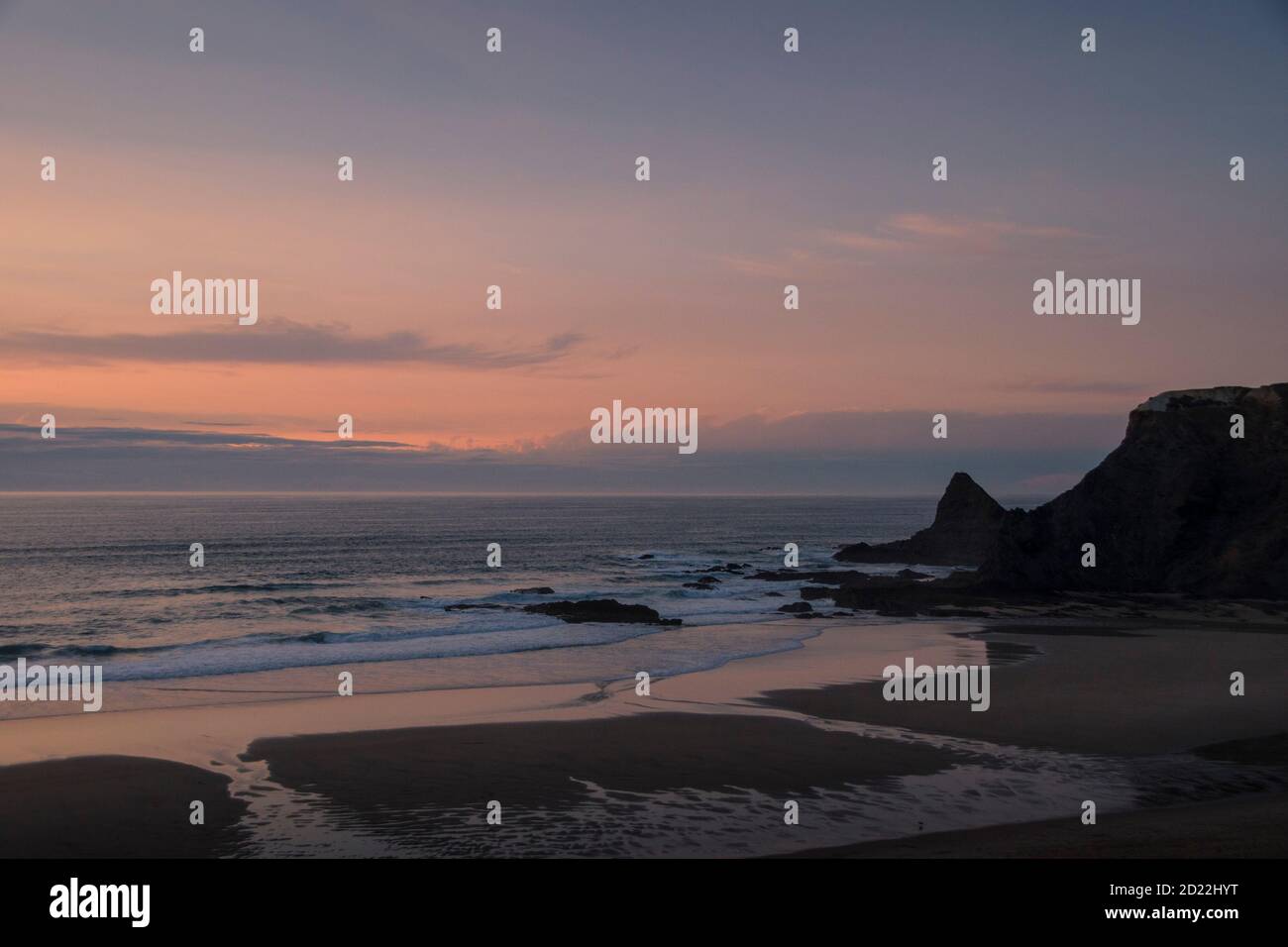 Ocean landscape at sunset, after the sun disappears, with pink tones, with the horizon line dividing the cloudy sky and the water Stock Photo