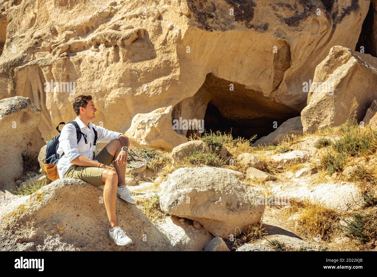 Tourist explorer sitting at rock and looking at rock site in Cappadocia Stock Photo
