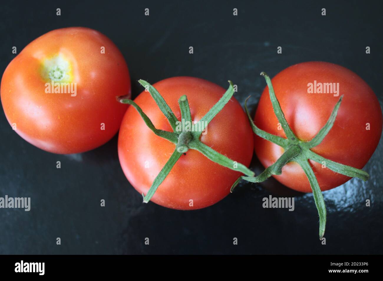 Close up ripe red tomatoes fresh juicy fruit harvested from organic garden bush home grown Summer for raw vegan vegetarian salad picnic birds eye view Stock Photo