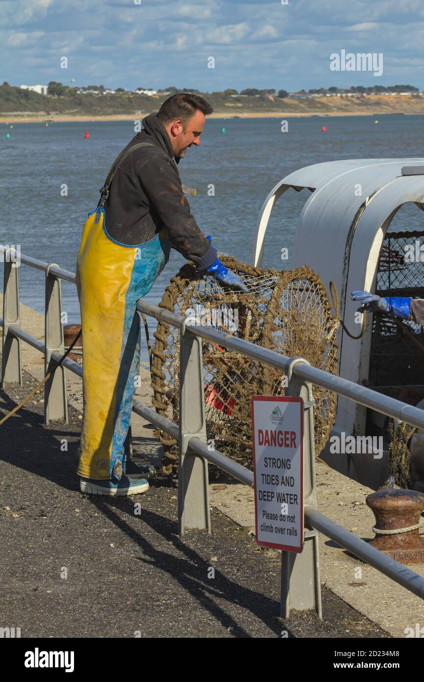 FishermanStanding On The Quayside Unloading Lobster Pots From A Fishing