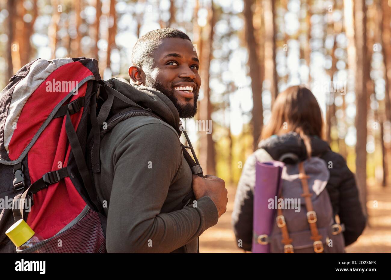 Happy black guy looking aside, hiking with girlfriend Stock Photo