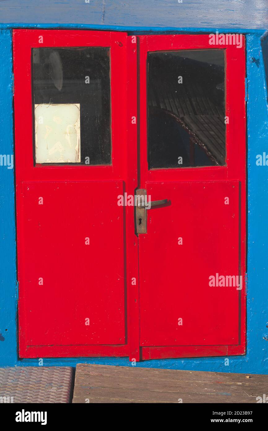 Colourful Old, Ancient Worn Red Painted Doors On The Back Of A Dutch Barge Painted Blue. Taken at Mudeford UK Stock Photo