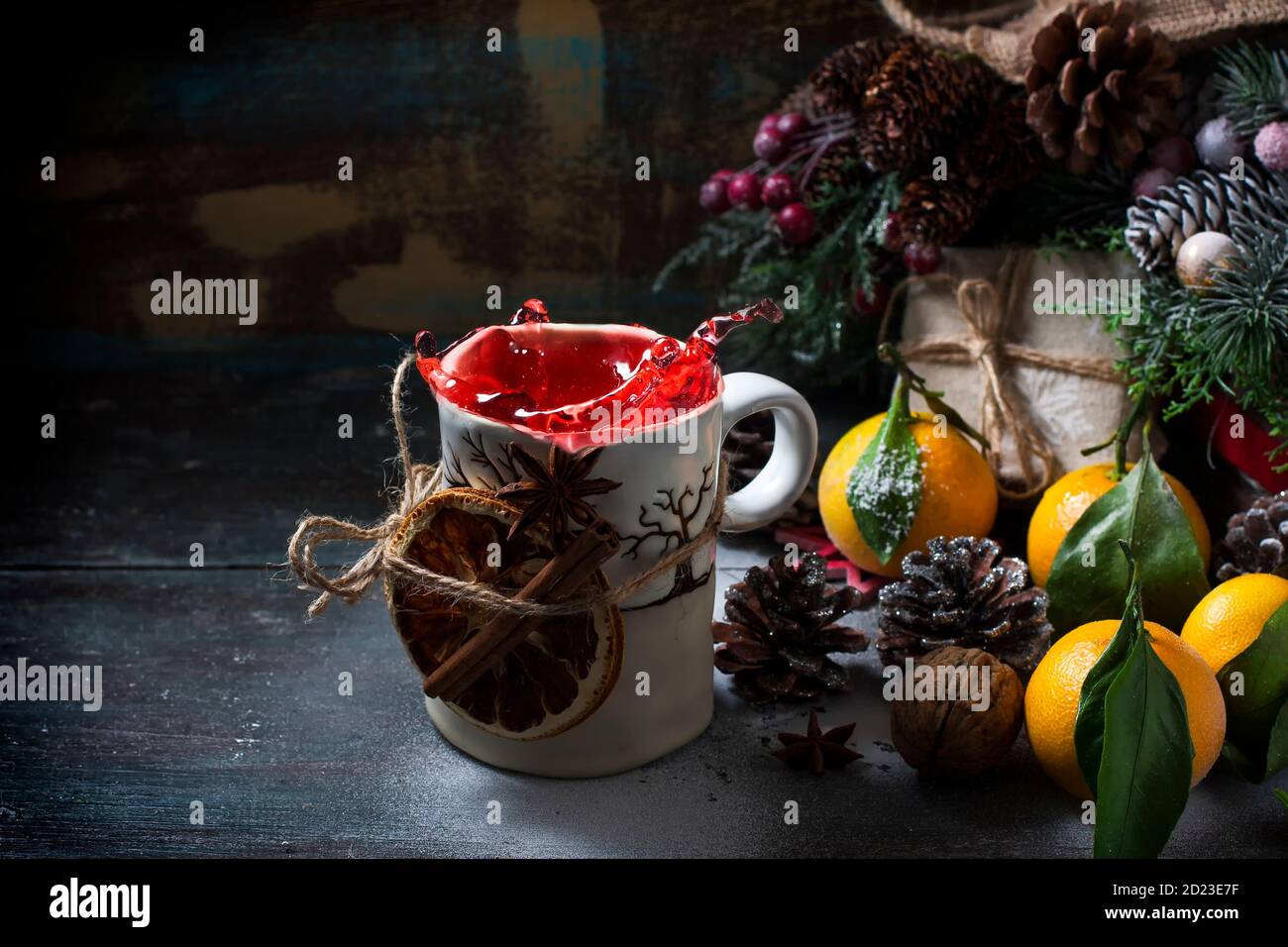 Mulled wine splashes and tangerines Christmas composition. Gift box, cones on a dark wooden background. Copy space Stock Photo