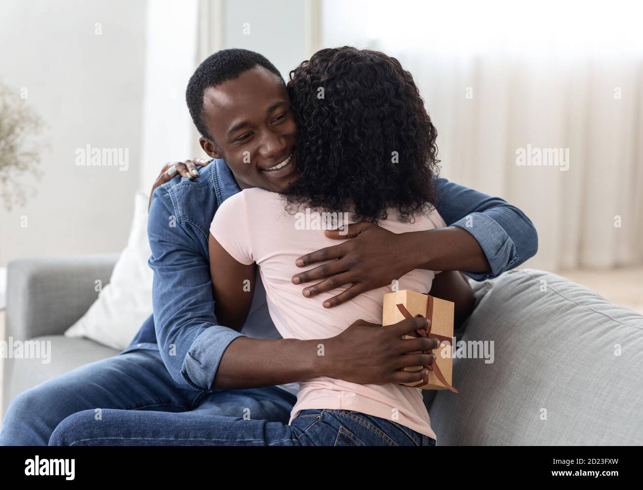 Glad african guy with present hugging his girlfriend Stock Photo - Alamy