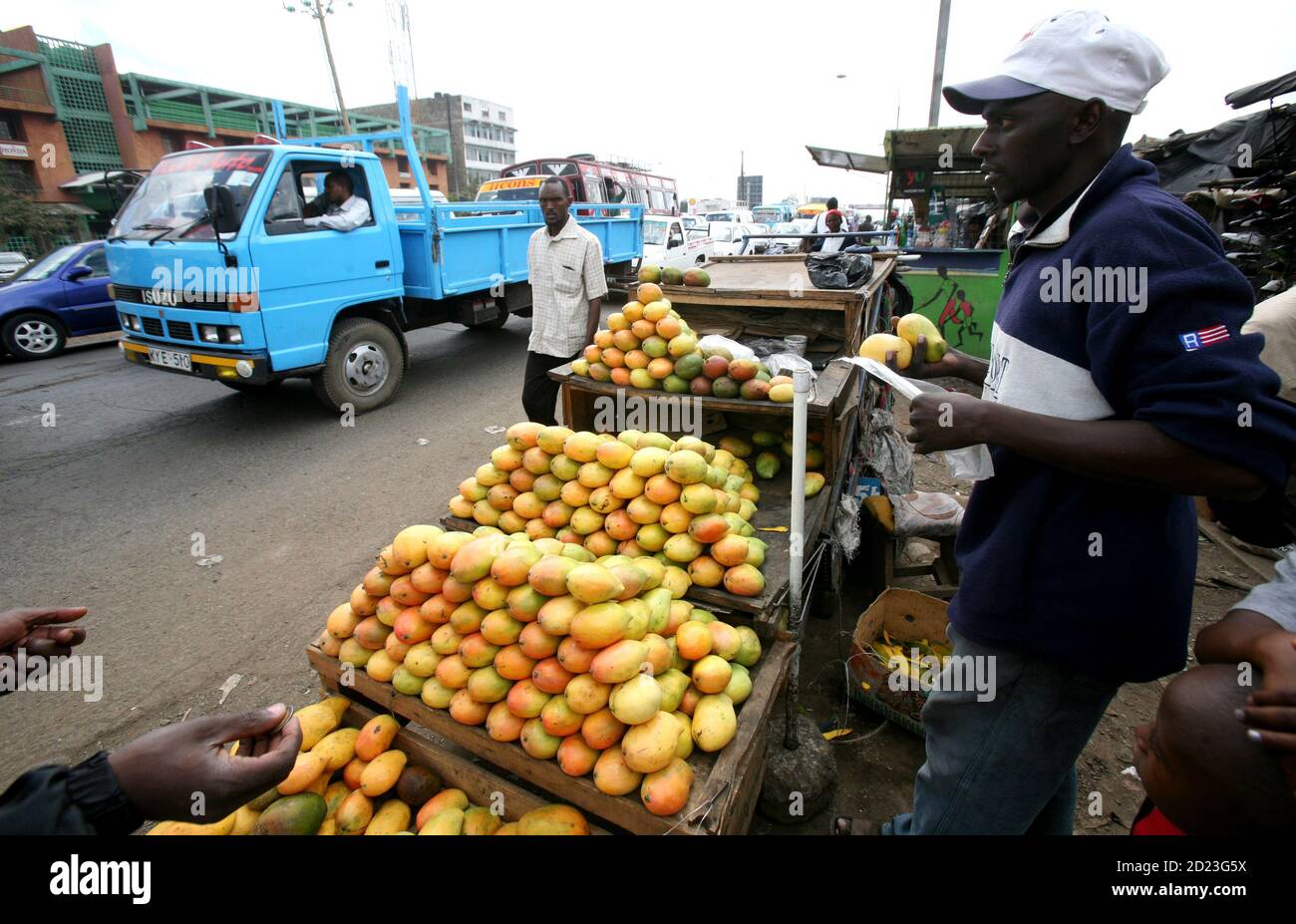 A trader sells mangoes next to moving traffic in Kenya's capital Nairobi, April 3, 2009. The global economic slump makes it even more important for African governments to help local businesses by cutting red tape in areas like customs, tax and registration, a continental investment body said on Friday. REUTERS/Thomas Mukoya (KENYA BUSINESS POLITICS) Stock Photo