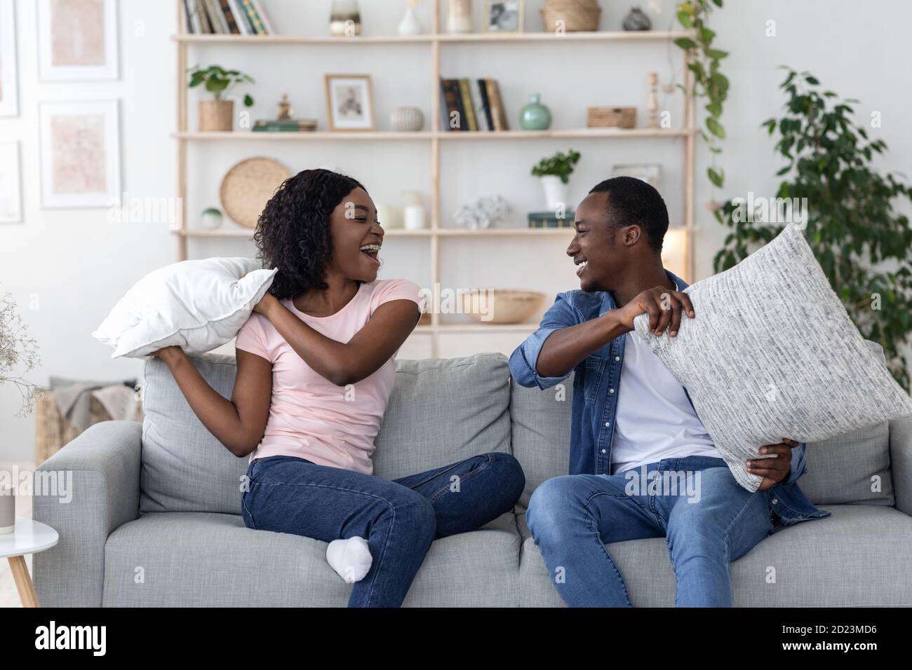 Happy loving black couple fighting with pillows in living room Stock Photo
