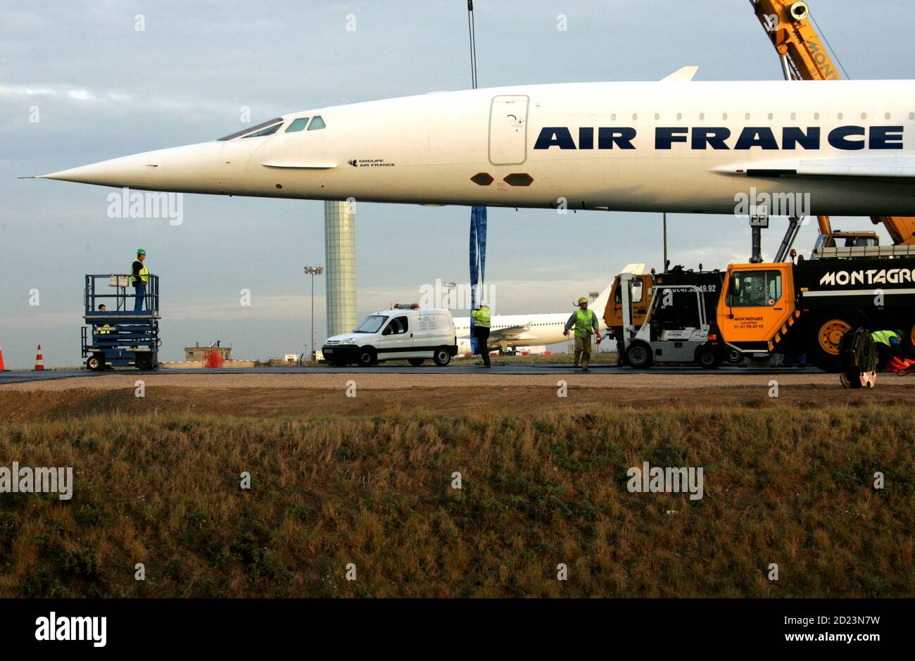 Employees prepare to lower the retired Air France Concorde number 5 by cranes onto pylons on the tarmac at the Roissy-Charles de Gaulle Airport, north of Paris October 19, 2005. The retired Concorde is placed on permanent display in an inclined position to simulate the take off of the supersonic passenger jet. Stock Photo