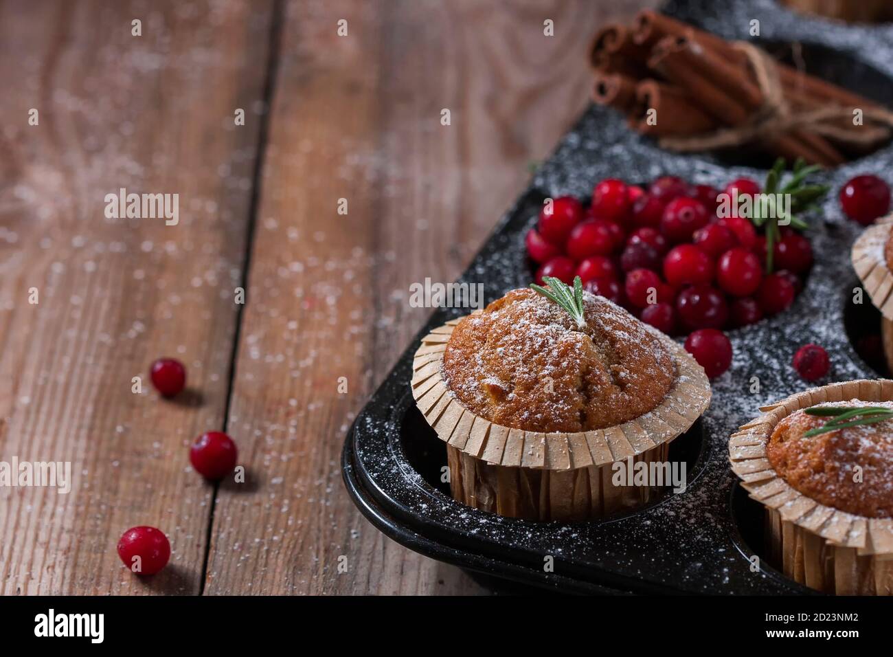 Fresh homemade Cranberry muffins in baking form on wooden table with Christmas decoration. Muffins in eco-friendly recyclable paper packaging. Stock Photo