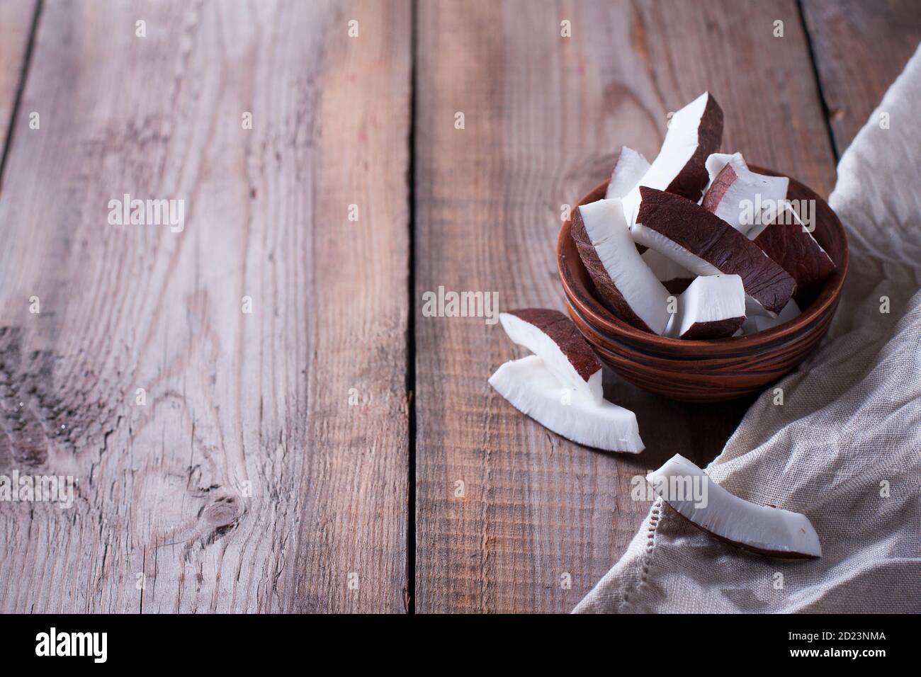 Ceramic bowl with coconut slices on a wooden background. Stock Photo