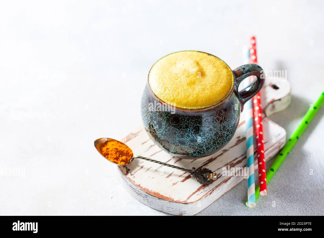 Cup of ayurvedic drink golden almond milk or turmeric latte with curcuma powder on white background. Natural detox beverage with spices. Stock Photo