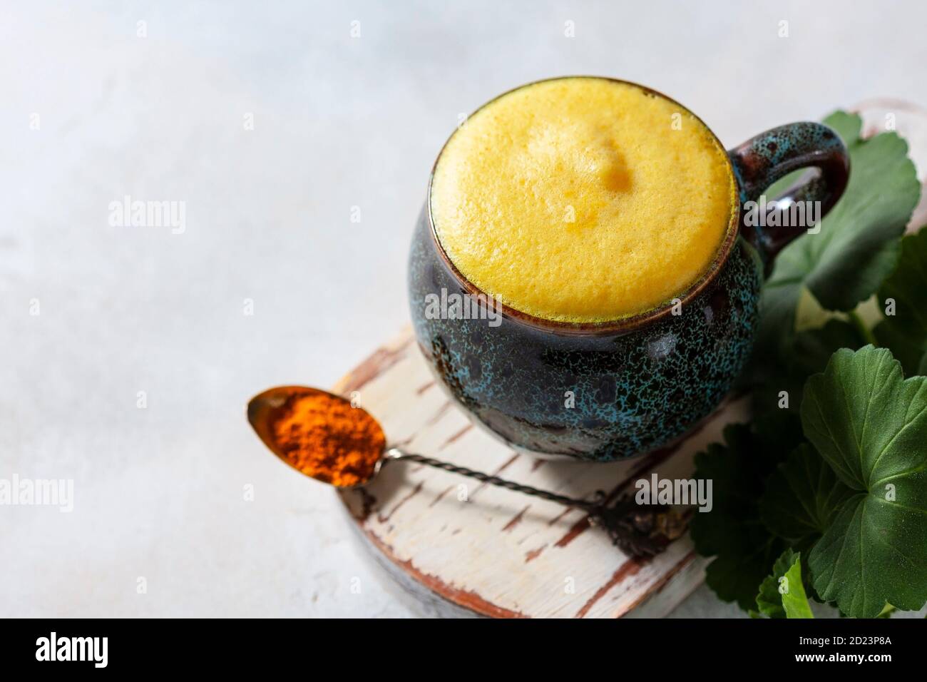 Cup of ayurvedic drink golden almond milk or turmeric latte with curcuma powder on white background. Natural detox beverage with spices. Stock Photo