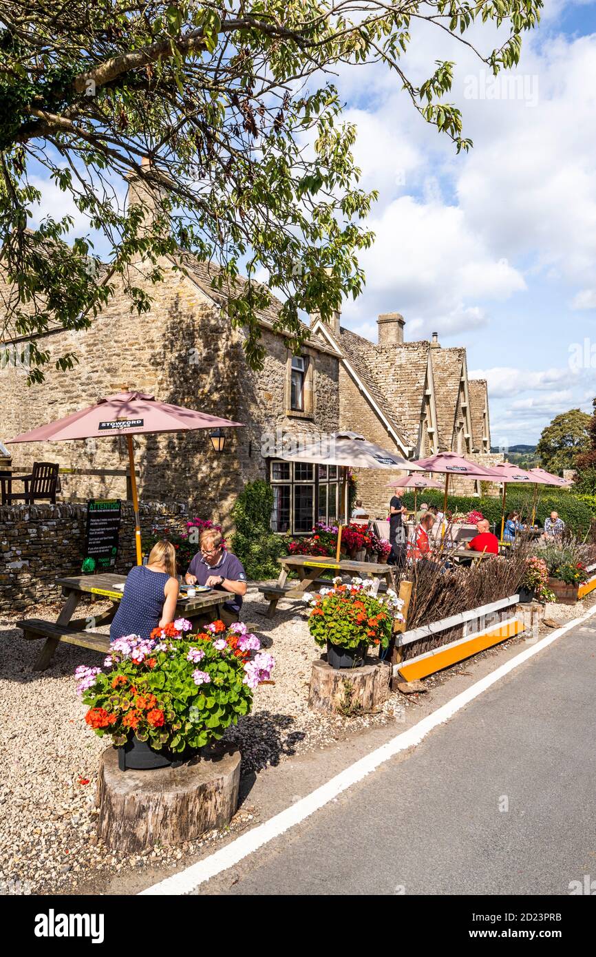 Socially distanced customers at the Carpenters Arms public house on a sunny day during Covid 19 restrictions in the Cotswold village of Miserden, Glos Stock Photo