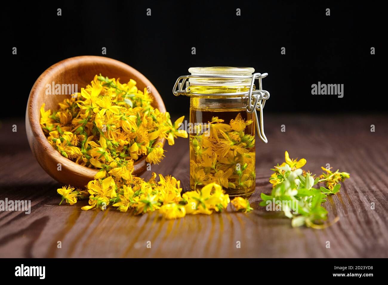 Glass jar with hypericum or St Johns wort oil extract and wooden bowl