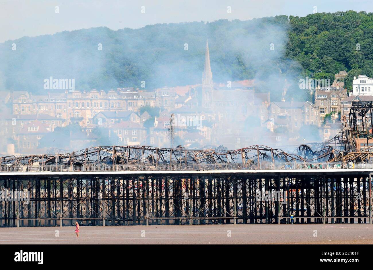 Holiday makers walk on the beach near the Grand Pier at Weston-Super-Mare in south west England July 28, 2008. Firefighters were called to a large blaze that swept through the historic pier at the Somerset seaside resort of Weston-super-Mare on Monday, police said. Flames and thick black smoke engulfed the structure and could be seen from the M5 motorway, several miles from the coast, a fire brigade spokeswoman said. REUTERS/Toby Melville (BRITAIN) Stock Photo