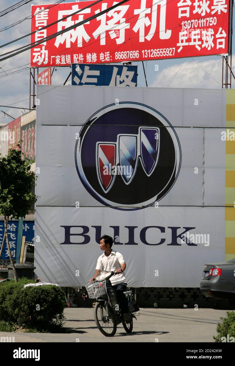 A man rides a motorized bicycle in front of a Buick poster outside a General Motors (GM) auto dealership in Beijing May 29, 2009. GM is facing imminent bankruptcy in the United States after bondholders rejected a debt-for-equity swap, a key part of the restructuring plan it needs to complete before a June 1 deadline imposed by the administration of President Barack Obama. Its China division, primarily two ventures with SAIC Motor, is profitable and self-sufficient, and able to fund its own daily operations and expansion, executives say. REUTERS/Christina Hu (CHINA TRANSPORT BUSINESS) Stock Photo