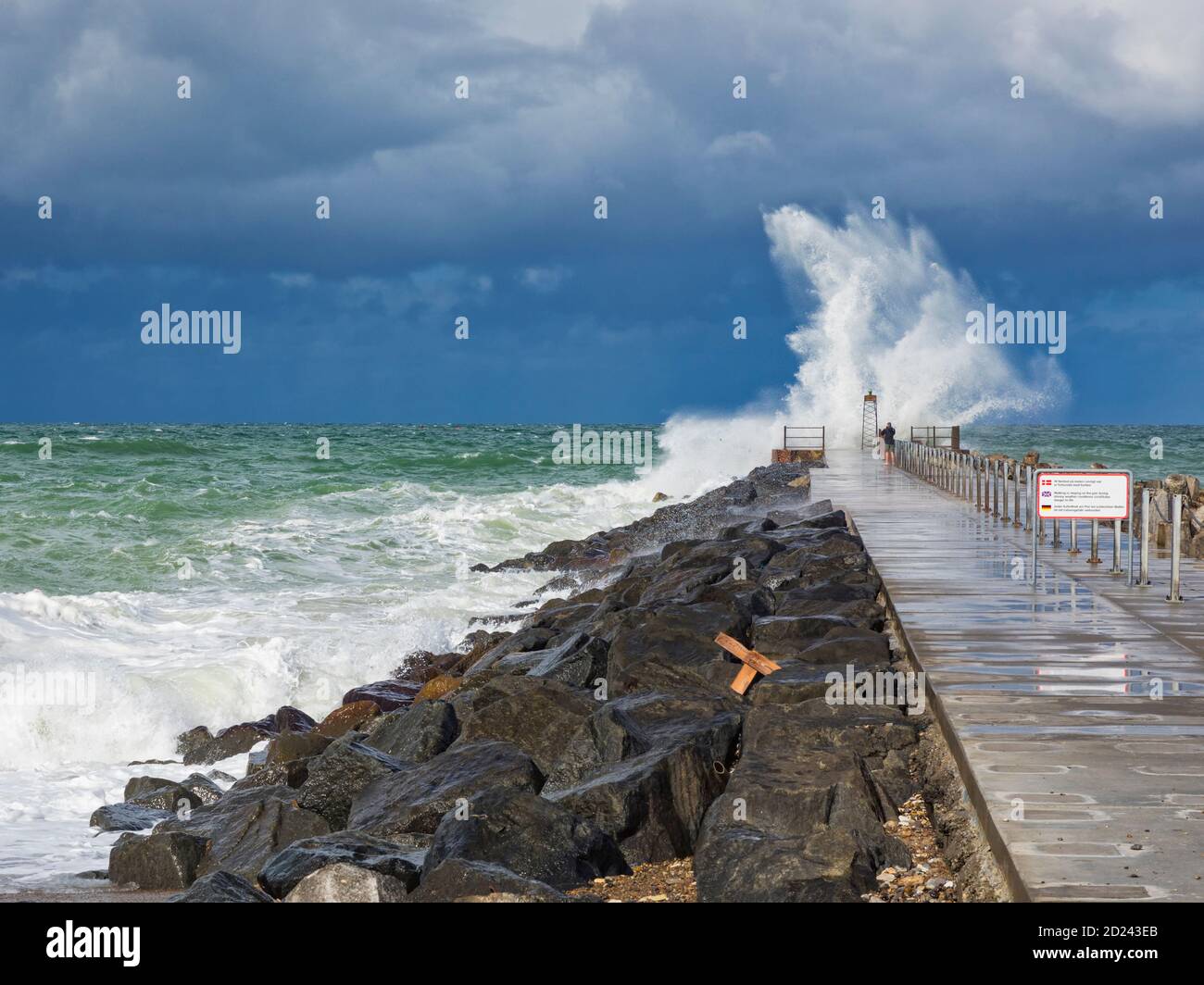 Incautious tourist in beach sandals on a pier at the North Sea during heavy weather Stock Photo